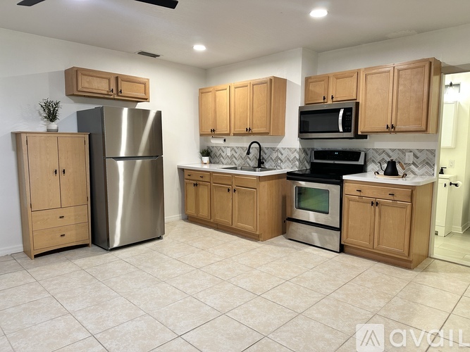 A kitchen with wooden cabinets and a stainless steel refrigerator.