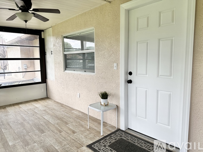 A white door is on the right side of a room with a fan on the ceiling.