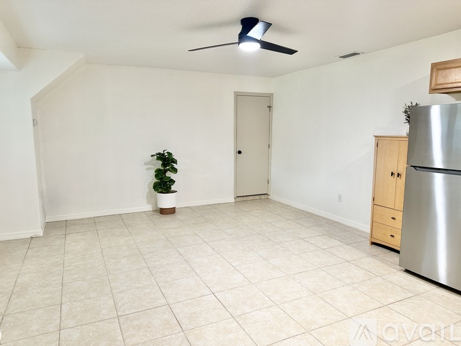 A room with a ceiling fan and a refrigerator.
