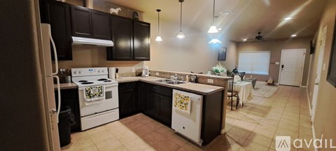 A kitchen with a white stove top oven and black cabinets.