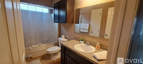 A bathroom with a toilet, sink, and mirror.