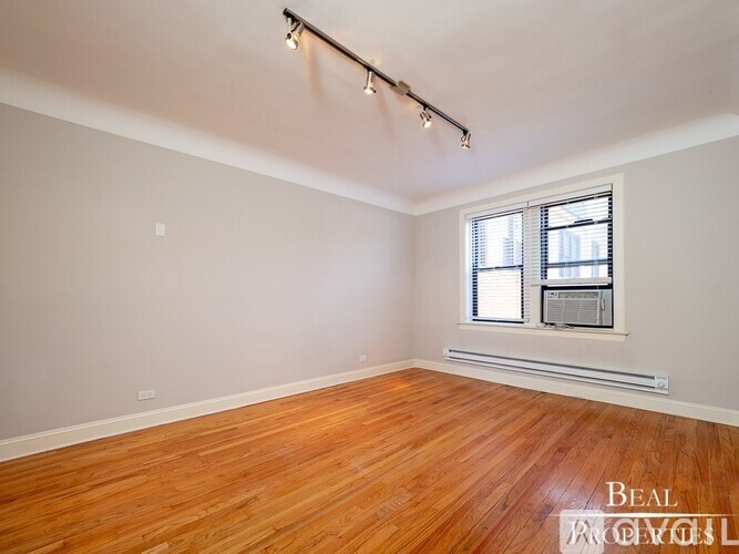 A room with wooden floors and a window with blinds.