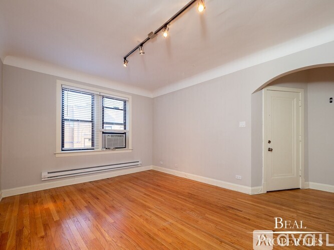 A room with wooden floors and a window with blinds.