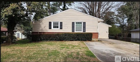 A beige house with a black fence and a green lawn.
