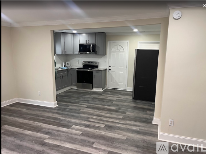 A kitchen with a black fridge and a black trash bin.