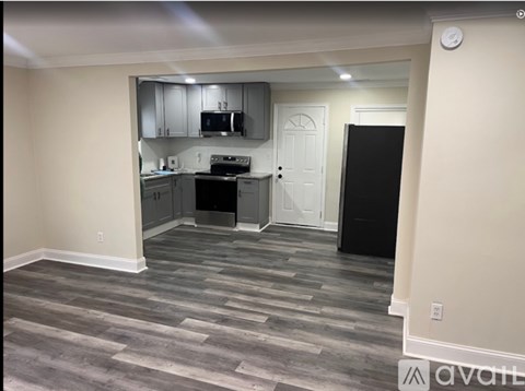 A kitchen with a black fridge and a black trash bin.