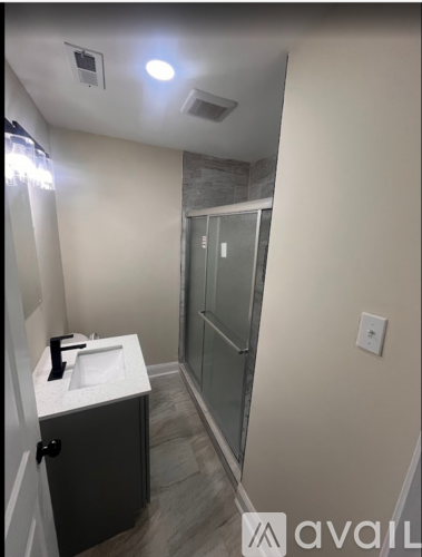 A bathroom with a sink, mirror, and shower.