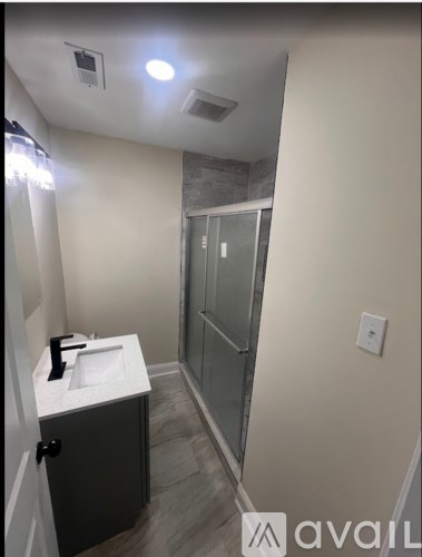 A bathroom with a sink, mirror, and shower.