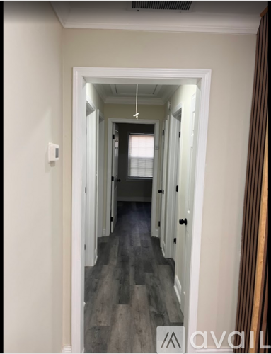 A hallway with a wooden floor and white walls.