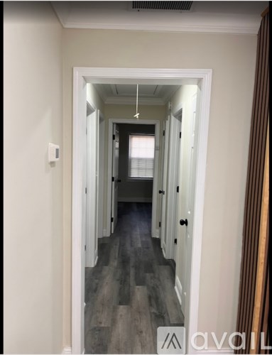 A hallway with a wooden floor and white walls.