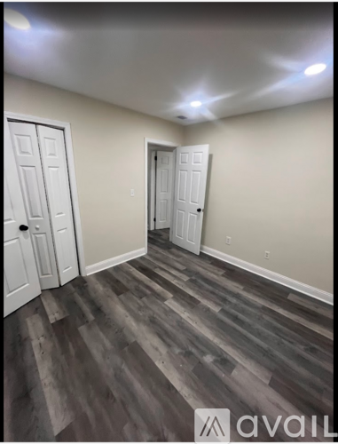 A room with wooden flooring and two doors.