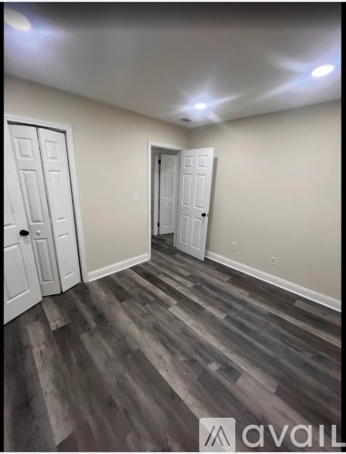 A room with wooden flooring and two doors.