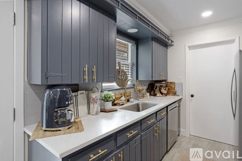 A kitchen with dark grey cabinets and a white countertop.