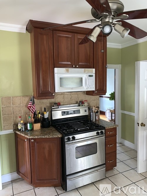 A kitchen with a stove, oven, microwave, and a fan.
