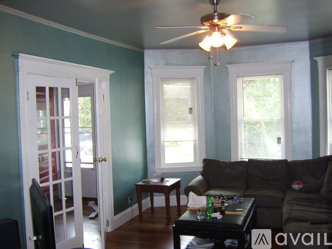 A living room with a couch, a chair, a coffee table, and a ceiling fan.