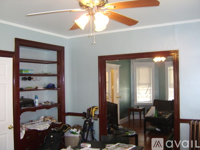 A room with a ceiling fan and a bookshelf filled with items.
