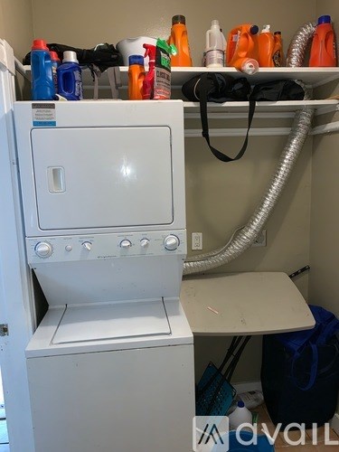 A white dryer is sitting in a small room with a hose coming out of the wall.