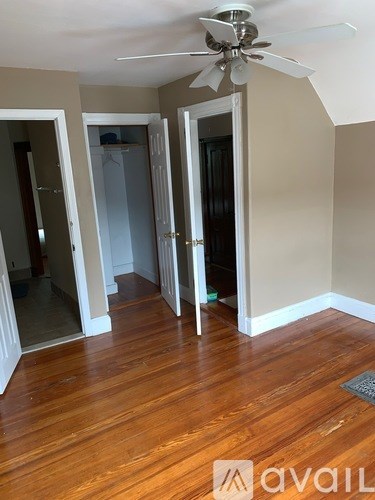 A room with a ceiling fan and wooden floors.