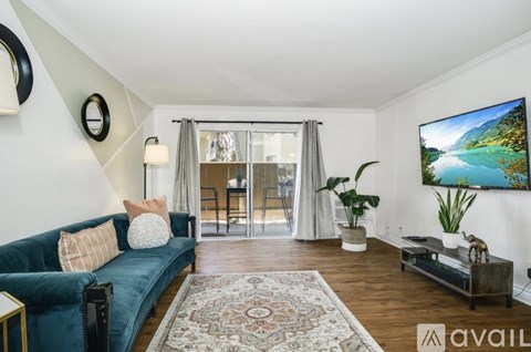 A living room with a blue couch, a flat screen TV, and a rug.