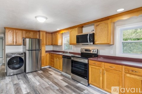 A kitchen with wooden cabinets and a stainless steel refrigerator.
