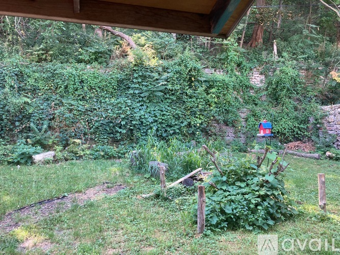 A garden with a wooden fence and a small red building in the background.