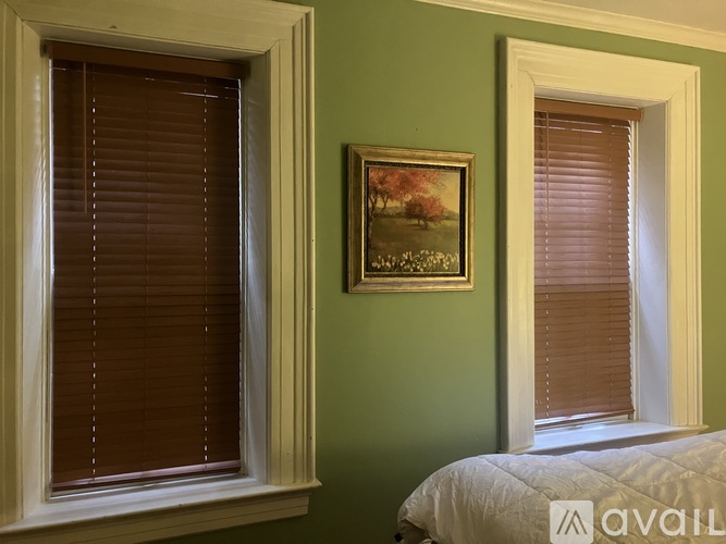 A bedroom with green walls and a picture of a tree in the corner.