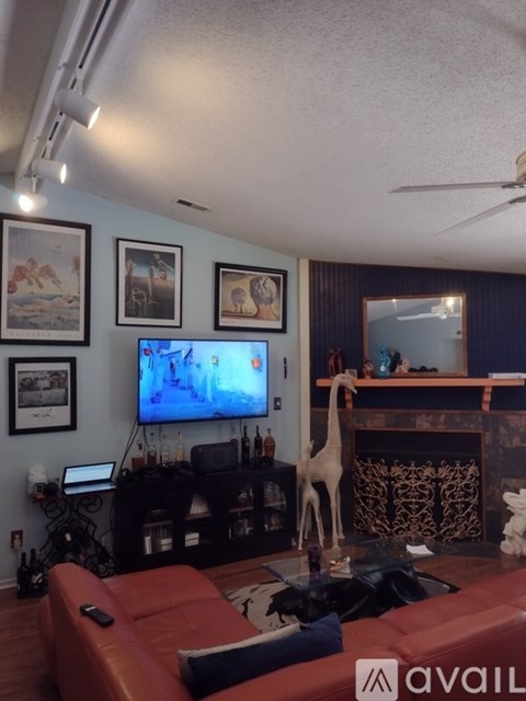 A living room with a red couch and a television on the wall.