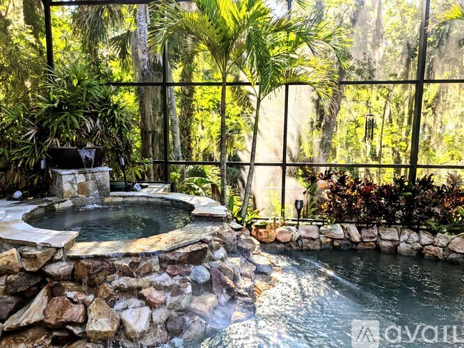 A hot tub is surrounded by rocks and palm trees.