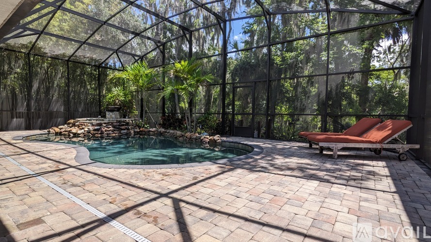 A pool surrounded by a glass wall with trees in the background.