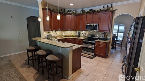 A kitchen with brown cabinets and a marble countertop.