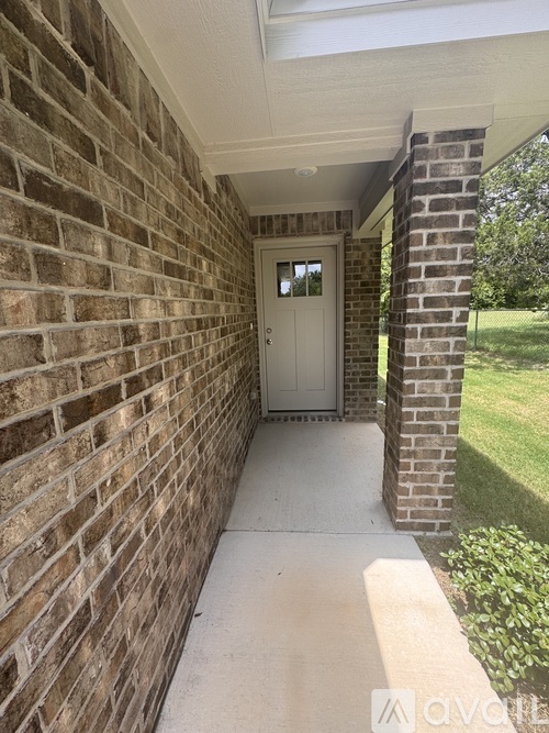 A white door is on the left side of a brick wall.