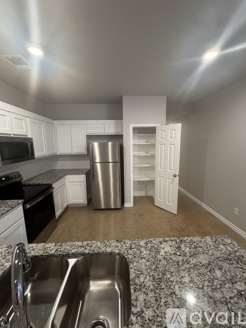 A kitchen with a stainless steel refrigerator and a granite countertop.