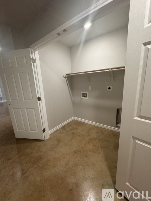 A white door is open to a hallway with a white wall and a white electrical outlet.
