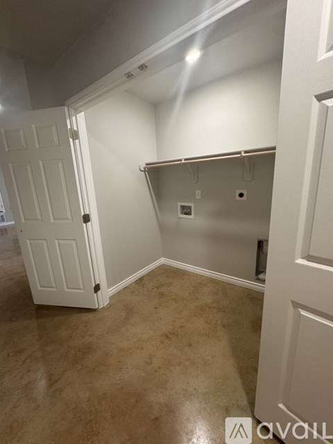 A white door is open to a hallway with a white wall and a white electrical outlet.