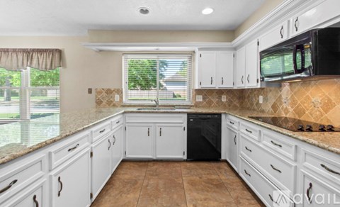 A kitchen with white cabinets and brown tiles.