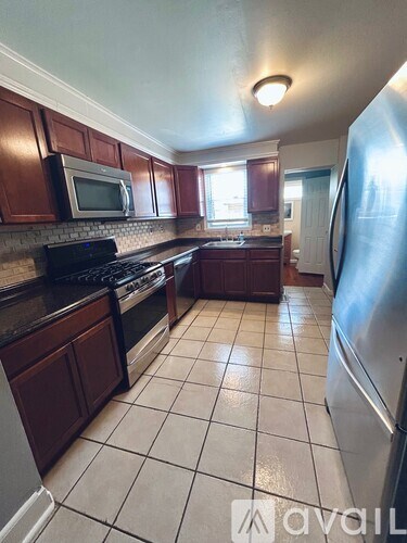 A kitchen with brown cabinets and a stainless steel refrigerator.