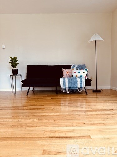 A living room with a black couch and a wooden floor.