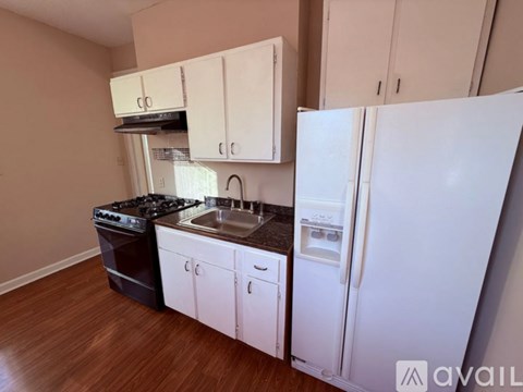 A kitchen with white cabinets and a white refrigerator.
