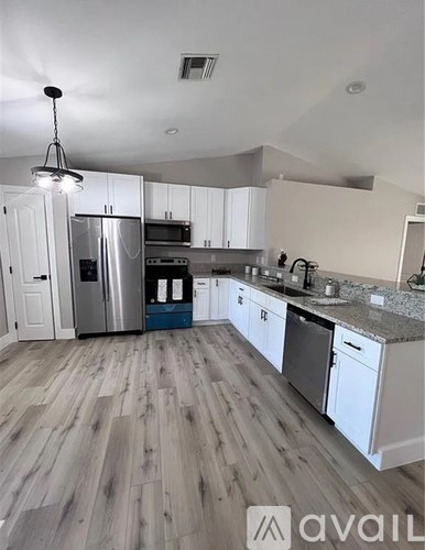 A kitchen with white cabinets and a wooden floor.