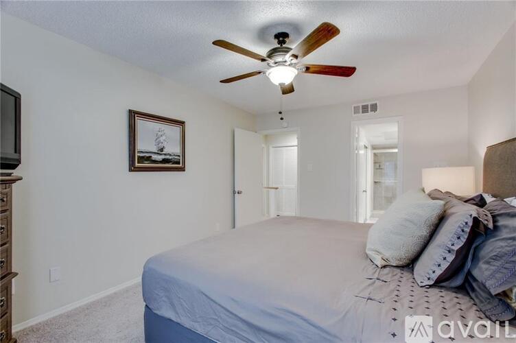 A bedroom with a bed, a ceiling fan, and a painting on the wall.