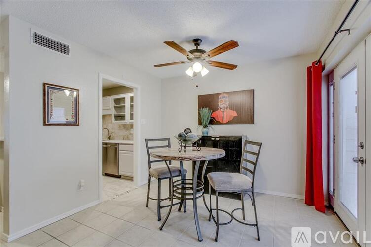 A dining room with a table set for two and a ceiling fan.