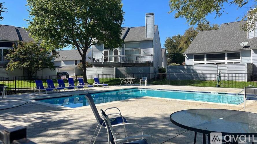 A pool with chairs around it and houses in the background.