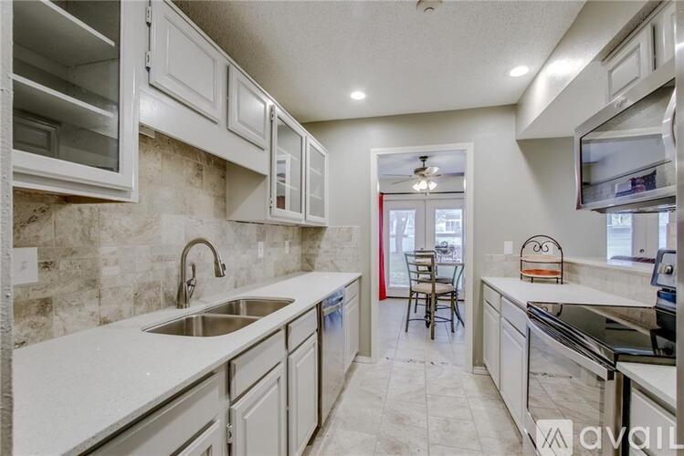 A kitchen with white cabinets and a marble backsplash.