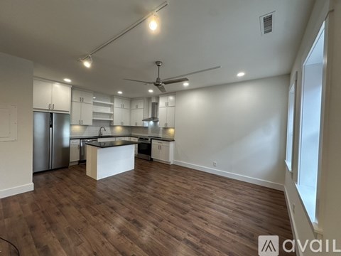 A spacious kitchen with a refrigerator, cabinets, and a countertop.