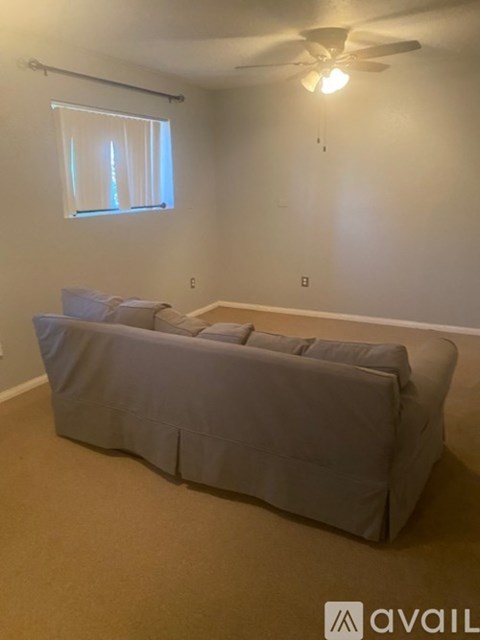 A bedroom with a bed covered in a grey sheet and pillows.