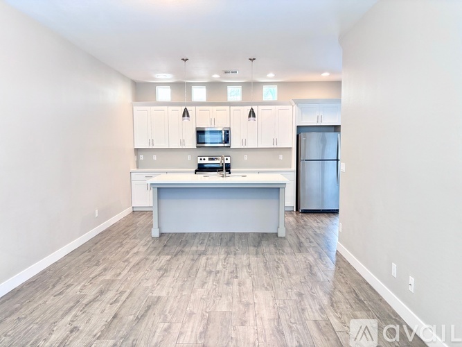 A kitchen with white cabinets and a wooden floor.