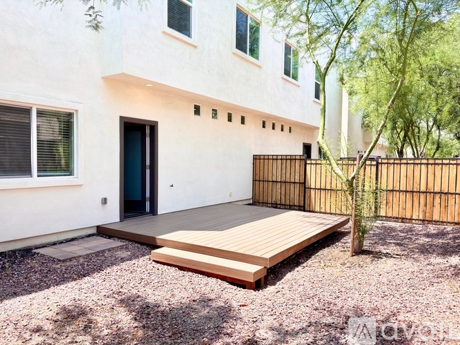 A modern house with a wooden deck and a tree.