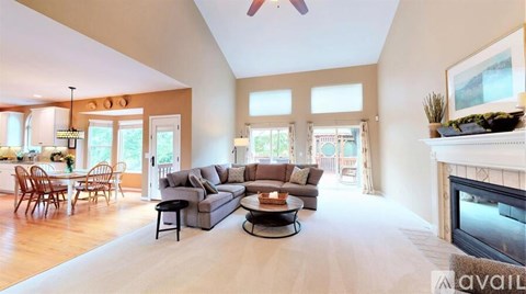 A living room with a grey sectional sofa, a fireplace, and a dining table with chairs.