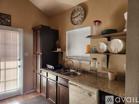 A kitchen with a black refrigerator and wooden cabinets.