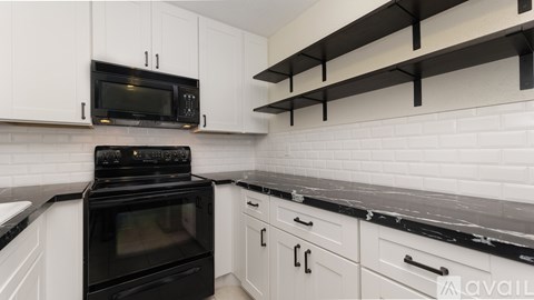 A black oven and microwave in a kitchen with white cabinets.
